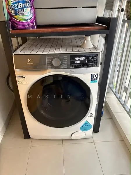 Laundry features: front-load washing machine in white, detergent storage on shelf above, tile flooring, grey shelving unit, visible drainage hose, clean white walls.