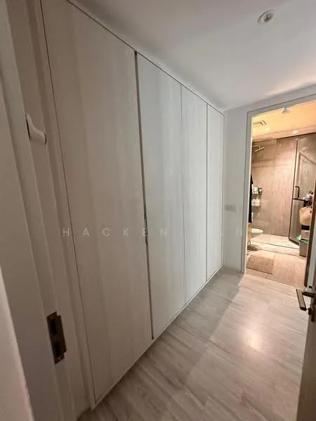 Room features: built-in wardrobes with sliding doors, light wood cabinetry, laminate flooring, neutral wall color, recessed lighting, doorway leading to bathroom, minimalist design; style: modern.