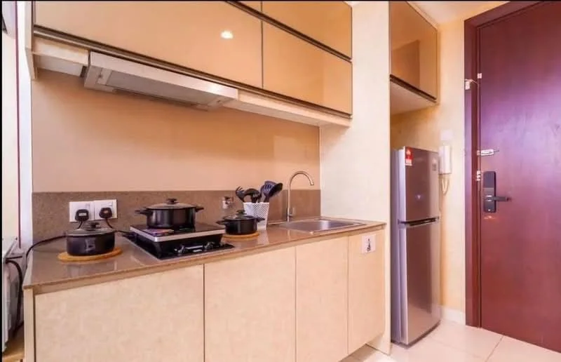 Kitchen features: laminate cabinetry in beige, granite countertop, single-bowl stainless-steel sink, chrome pull-down faucet, built-in stove with 2 burners, stainless-steel range hood, stainless-steel fridge, wall-mounted electrical outlets, kitchen utensils in holder, tile backsplash, light-colored wall, white tiled flooring; style: modern.