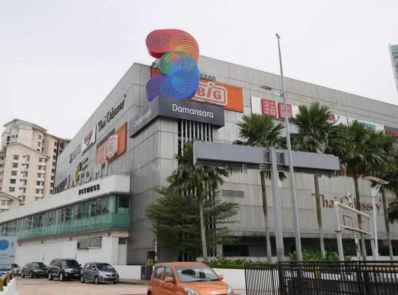Exterior type: shopping mall; features: grey metal facade, large signage, palm trees in landscaping, multiple storeys, glass windows, outdoor parking area, fitness center visible, entrance with awning; style: modern.