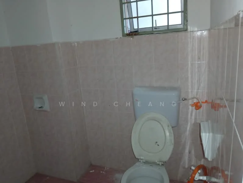 Bathroom features: pink tiled walls, pink tiled flooring, one-piece toilet, small window, toilet paper holder, orange plumbing fixtures.