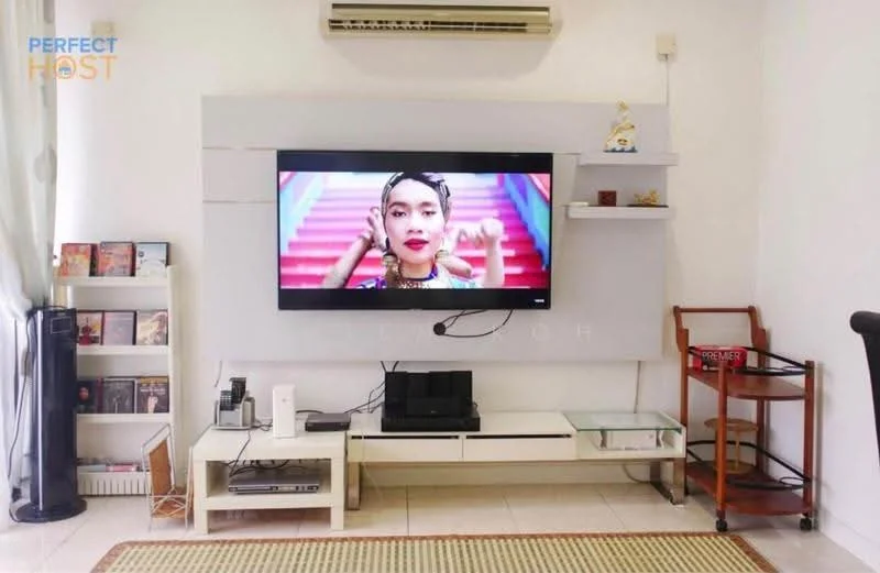 Living features: wall-mounted TV, white feature wall, floating shelves, light-colored tiled flooring, air conditioning unit, black entertainment unit, wooden side table, bookshelf with books and decor, decorative items on shelves, sofa, floor lamp; style: modern.