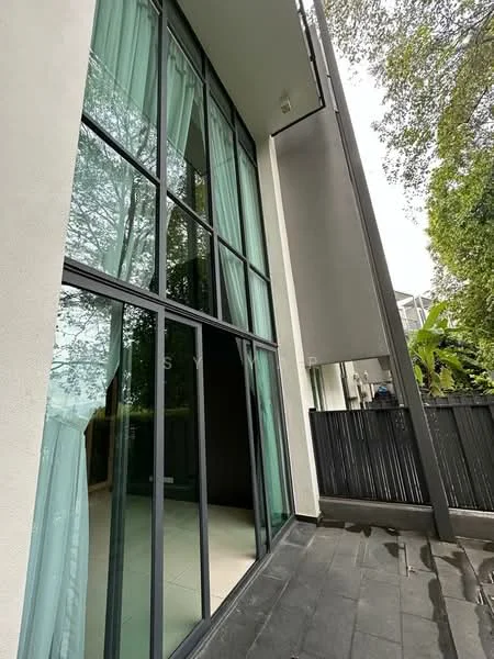 Exterior features: large floor-to-ceiling windows, black metal framing, light green sheer curtains, smooth concrete wall, dark stone flooring, surrounding greenery, modern architectural design; style: modern.
