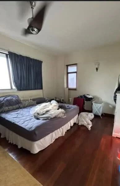 Bedroom features: queen-size bed with grey bedding, wooden flooring, white walls, dark blue curtains, single window, ceiling fan, nightstand, laundry basket, white bedding on the floor, wall sconce.