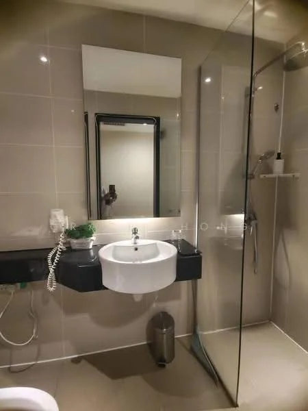 Bathroom features: wall-mounted basin, chrome basin mixer faucet, large framed mirror, glass shower enclosure, rain shower head, handheld shower, toilet, black countertop, light beige tiled walls, light beige tiled flooring, small potted plant, wall-mounted phone, waste bin; style: modern.