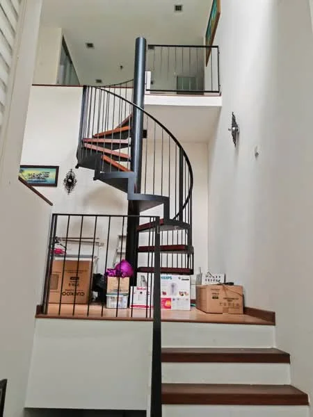 Room features: spiral staircase with black metal railing, wooden steps, white painted walls, high ceiling, decorative wall sconces, boxes stacked on stairs, framed artwork on wall, open upper landing; style: modern.