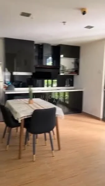 Dining features: dining table with tablecloth, 4 black dining chairs, wooden flooring, black cabinetry, white countertop, built-in kitchen appliances, greenery decor, open layout; style: modern.