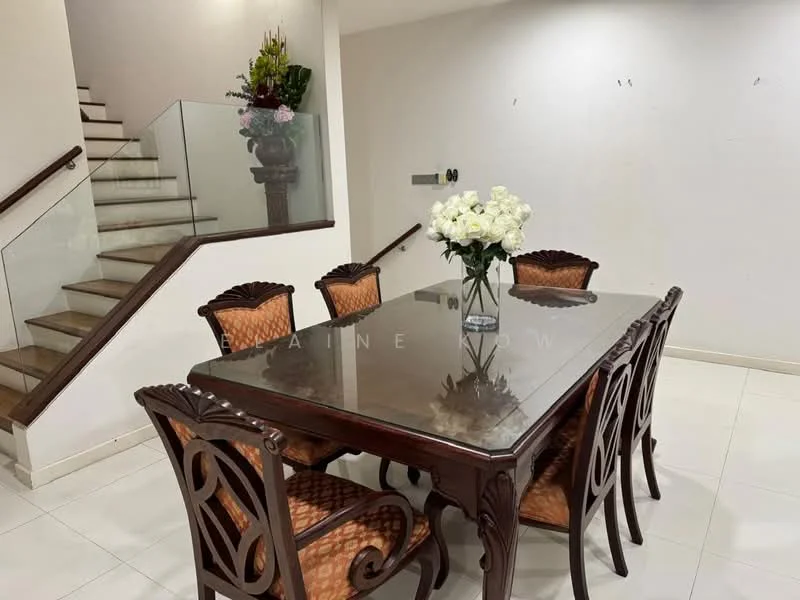 Dining features: wooden dining table with polished surface, 6 upholstered dining chairs with intricate carvings, white painted walls, tile flooring, decorative flower arrangement in vase, staircase with wooden handrail, glass railing, natural light from upper level; style: traditional.