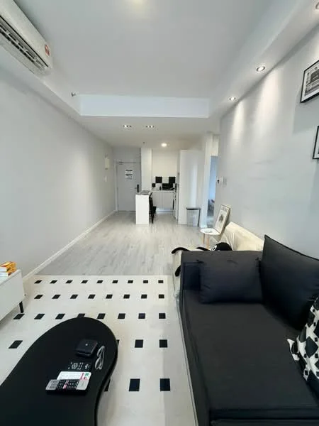 Living features: grey painted walls, light wood flooring, 3-seater fabric sofa in dark grey, black coffee table with geometric pattern, wall-mounted air conditioning unit, recessed downlights, decorative wall art, open layout to dining area; style: modern. Room features: white walls, light wood flooring, dining area visible in background.