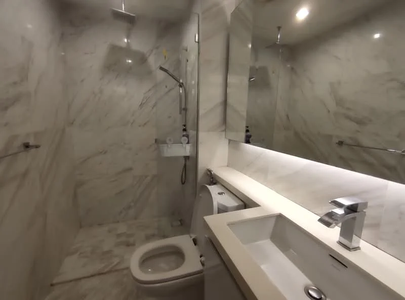 Bathroom features: marble wall cladding, marble flooring, single-sink vanity with white countertop, chrome basin mixer faucet, framed mirror, one-piece toilet, walk-in shower with rain shower head, glass shower enclosure, recessed LED downlights; style: modern.