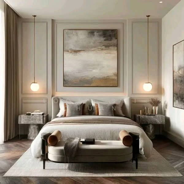 Bedroom features: king-size bed with upholstered headboard, light grey bedding, two bedside tables with stone bases, pendant lights hanging from the ceiling, abstract artwork on the wall, decorative vases on bedside tables, area rug with neutral tones, wooden herringbone flooring, large windows with sheer curtains, wall paneling with decorative molding; style: modern.