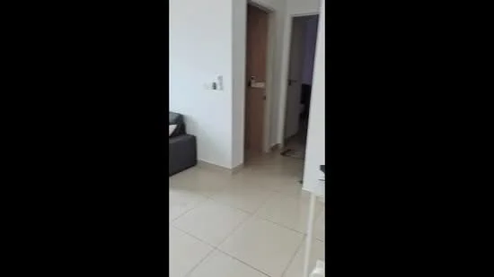 Room features: light-colored painted walls, cream floor tiles, sofa in dark color, doorway leading to another room, door frame, neutral decor, natural light from doorway; style: modern.