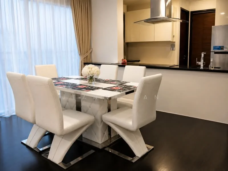 Dining features: 6-seater dining table with white upholstered chairs, tabletop with decorative pattern, dark wood flooring, floor-to-ceiling sheer curtains, kitchen island visible in background, modern pendant light above table, white walls, open kitchen layout; style: modern.