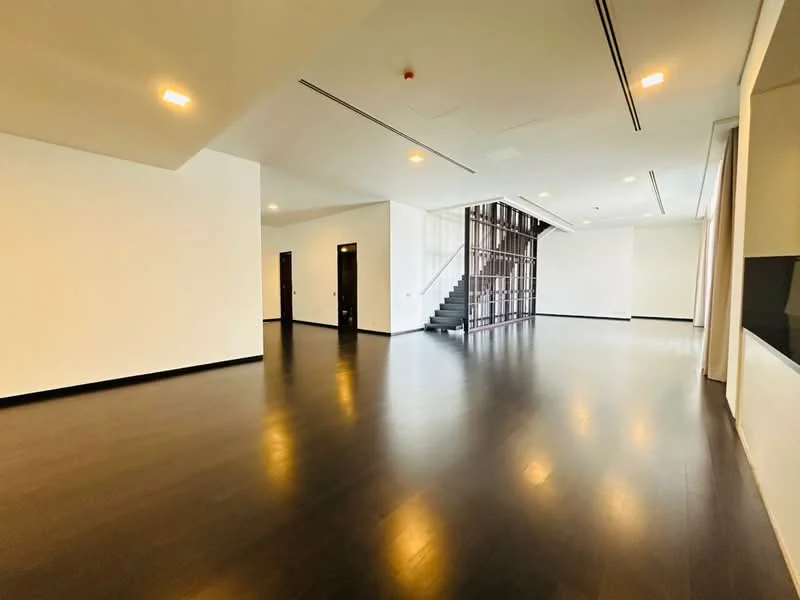 Room features: dark hardwood flooring, white painted walls, large windows, staircase with metal railing, recessed ceiling lights, open layout, high ceiling, no visible furniture; style: modern.