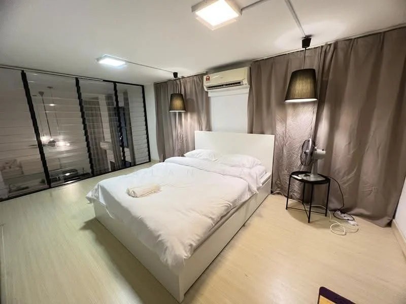 Bedroom features: king-size bed with white bedding, two bedside lamps with black shades, wooden flooring, air conditioning unit on wall, floor fan, curtains in light brown, white wall, black side table; style: modern.