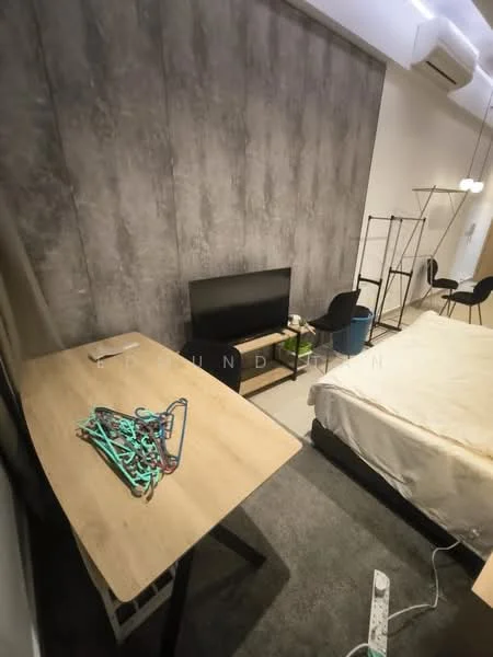Bedroom features: grey accent wall, light wood flooring, queen-size bed with white bedding, black TV console, flat-screen TV, wooden desk, black chair, clothes rack, area rug, recessed ceiling lights, wall-mounted air conditioning unit; style: modern.