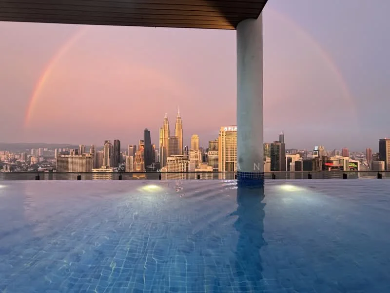 Exterior type: swimming pool deck; features: infinity pool, city skyline view, illuminated pool lights, surrounding high-rise buildings, rainbow in the sky, sunset lighting; style: modern.