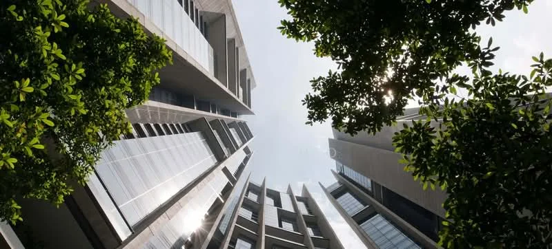 Exterior type: high-rise condominium; features: glass curtain wall, exposed concrete facade, vertical fins, recessed balconies, surrounded by greenery, modern architectural design; style: modern.