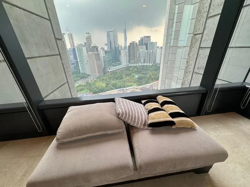 Room features: large window with city skyline view, grey fabric sofa with cushions, neutral-toned upholstery, stone flooring, black window frames, roller blinds; style: modern; view: city.