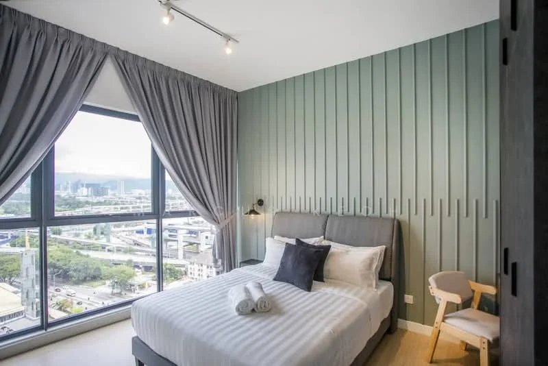 Bedroom features: king-size bed with grey upholstered headboard, white bedding with decorative pillows, floor-to-ceiling windows, grey curtains, green accent wall with vertical paneling, light wood flooring, wall-mounted reading light, small wooden chair, decorative towels, city view from window; style: modern; view: city.