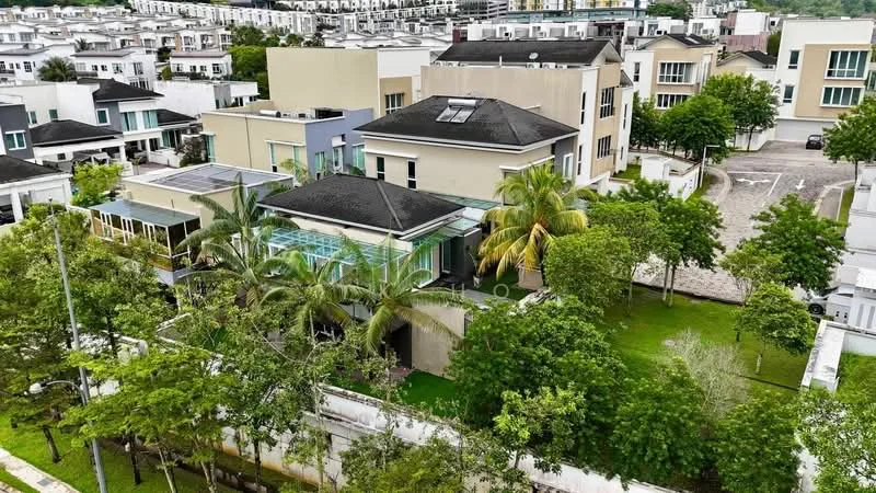 Exterior type: detached bungalow; features: flat roof, cream painted facade, large windows, manicured lawn, mature trees, surrounded by greenery, outdoor patio area, swimming pool visible, driveway with interlocking pavers, adjacent to other residential buildings; style: modern.