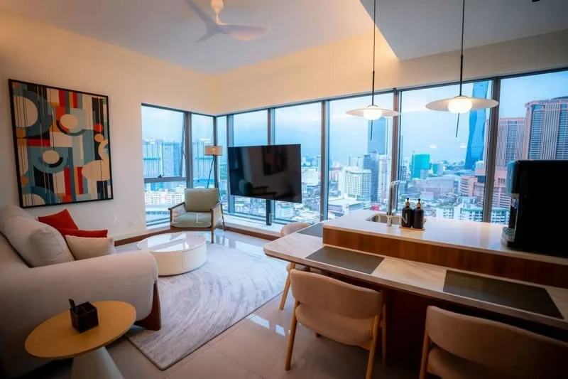 Living features: floor-to-ceiling windows, city view, 3-seater fabric sofa in light grey, round coffee table, TV console, wall-mounted TV, area rug with geometric pattern, ceiling fan, pendant lighting, decorative wall art; style: modern. Dining features: dining table with wooden surface, upholstered dining chairs, bar counter with seating, wine bottles on counter; style: modern.