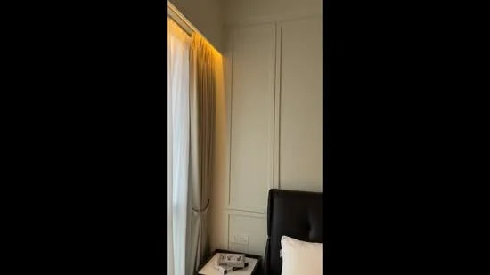 Bedroom features: white painted walls, curtains, bedside table, decorative wall paneling, upholstered headboard, bed linens, ambient lighting, floor-to-ceiling window; style: modern.