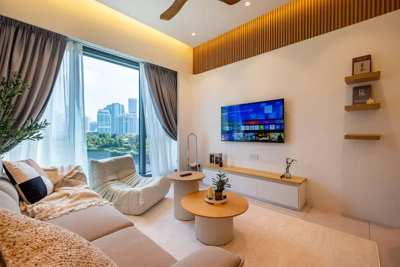 Living features: floor-to-ceiling windows, city skyline view, beige fabric sofa, two round coffee tables, light-colored area rug, wall-mounted TV, white media console, wooden feature wall, ceiling fan with light, curtains, decorative wall shelf, indoor plant; style: modern; view: city.