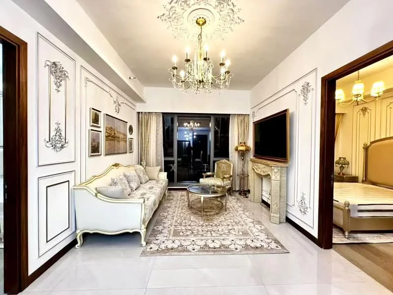 Living features: white painted walls with decorative moulding, marble flooring, chandelier with multiple bulbs, 3-seater white fabric sofa with ornate detailing, glass coffee table with gold accents, area rug with intricate pattern, wall-mounted TV, decorative wall art, large sliding glass door leading to balcony, crown moulding on ceiling; style: luxury. Room features: wooden door frames, decorative wall paneling.