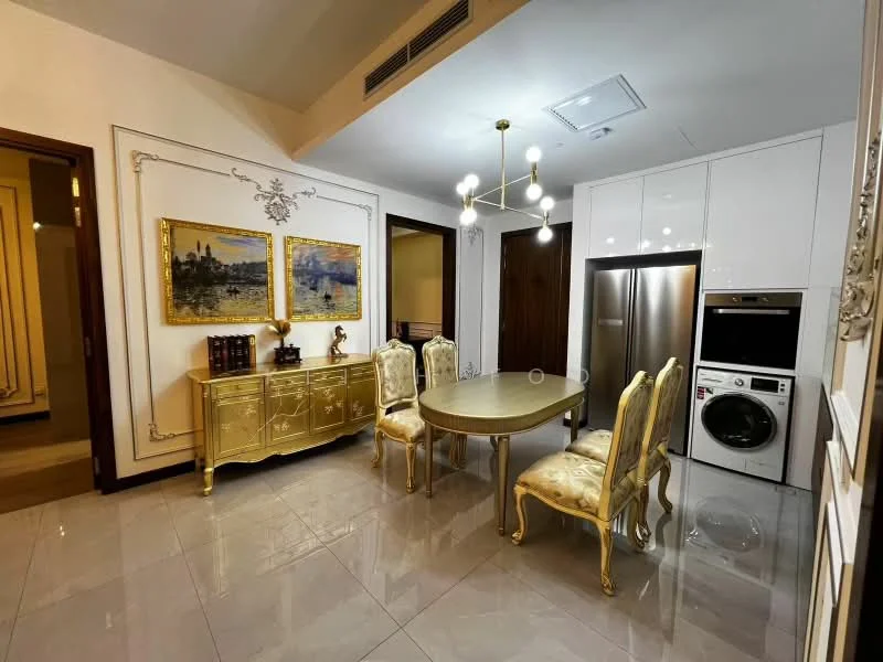 Dining features: round dining table, golden dining chairs with upholstery, golden sideboard with decorative elements, stainless-steel fridge, front-load washing machine, white cabinetry, marble tile flooring, recessed ceiling lights, decorative wall art, wall-mounted air conditioning unit; style: luxury.