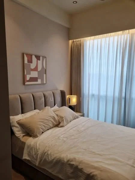 Bedroom features: queen-size bed, upholstered headboard, white bedding, decorative artwork on wall, curtains with sheer fabric, nightstand with lamp, soft lighting, neutral wall color, carpeted flooring; style: modern.