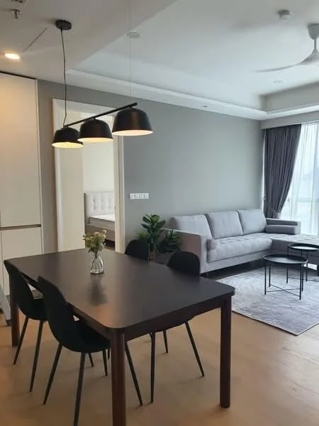 Dining features: 4-seater dining table, black dining chairs, pendant lighting with three black shades, wooden flooring, decorative vase with flowers, plant in pot, open layout, grey accent wall; style: modern. Living features: grey fabric sofa, coffee table, area rug, floor-to-ceiling windows with sheer curtains, wall-mounted TV, light-colored walls, ceiling fan, natural light; style: modern.