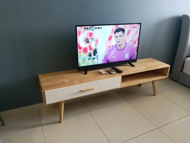 Room features: flat-screen TV on TV console, wooden TV console with white drawer, light-colored wooden legs on console, cream-colored wall, grey accent wall, glossy tile flooring, remote control on console, mobile phone on console, decorative items on console; style: modern.