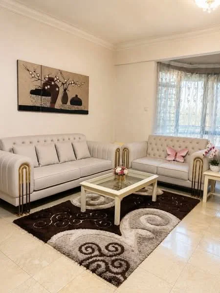 Living features: light-colored fabric sofa with tufted back, 2-seater fabric sofa, glass coffee table, area rug with abstract pattern, decorative wall art with floral design, curtains with sheer fabric, wall-mounted light fixture, cream painted walls, marble tile flooring; style: modern.