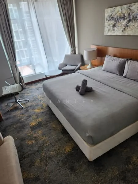 Bedroom features: king-size bed with grey bedding, upholstered headboard, two bedside lamps, floor-to-ceiling windows with sheer curtains, light grey walls, carpet flooring with abstract pattern, armchair, small round coffee table, decorative artwork on wall, side table, throw pillow on bed; style: modern; view: city.