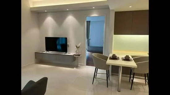Living features: white painted walls, recessed downlights, light-coloured tile flooring, wall-mounted TV, TV console, decorative plant on side table, open layout to dining area, neutral colour scheme; style: modern. Dining features: 4-seater dining table, upholstered dining chairs, kitchen counter with bar stools, light-coloured cabinetry, glass backsplash; style: modern.