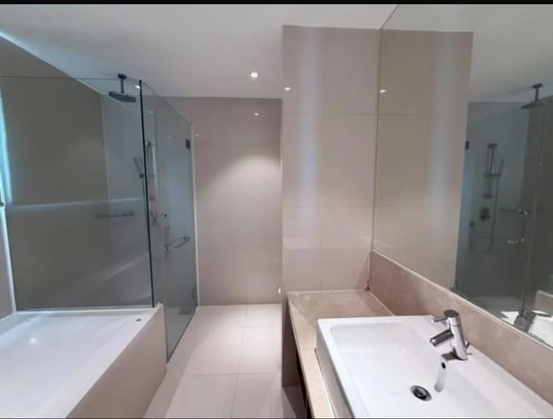 Bathroom features: walk-in shower with glass enclosure, freestanding bathtub, single-sink vanity with stone countertop, chrome basin mixer faucet, wall-mounted showerhead, recessed downlights, light-colored tile flooring, neutral painted walls, large mirror above vanity; style: modern.