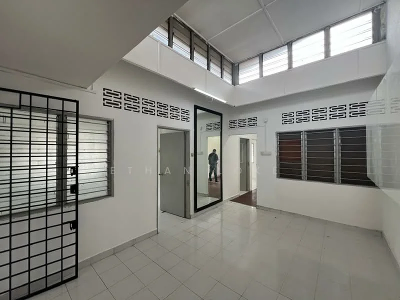 Room features: white painted walls, grey tiled flooring, large glass mirror, multiple windows with metal grilles, ceiling with fluorescent lighting, open layout, doorway leading to another room, sliding window, corner windows; style: modern.