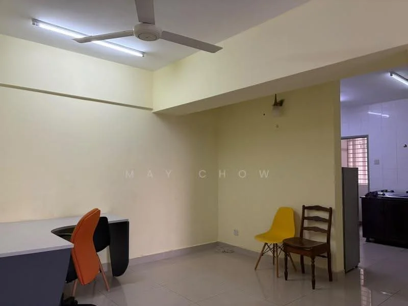 Room features: yellow painted walls, white ceiling, ceiling fan, tile flooring, two chairs (one yellow, one brown), black desk, open layout, kitchen area visible in background; style: modern.