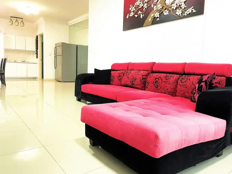 Living features: L-shape sectional sofa in pink and black, coffee table, wall-mounted artwork with floral design, cream painted walls, glossy tile flooring, recessed ceiling lights, visible kitchen area in background, stainless-steel fridge; style: modern.