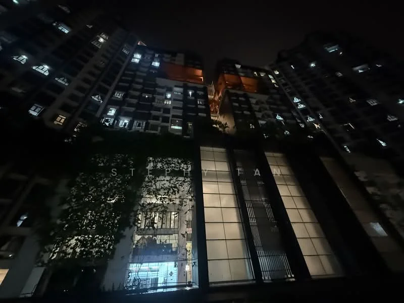 Exterior type: high-rise condominium; features: glass curtain wall, illuminated facade, vertical fins, recessed balconies, landscaped entrance, multiple storeys, night lighting, surrounded by greenery; style: modern.