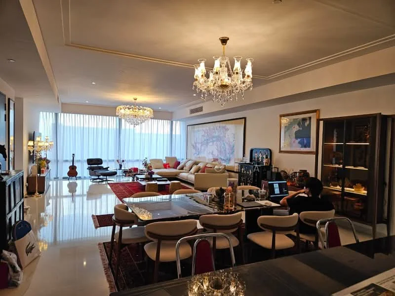 Living features: chandelier with multiple bulbs, recessed downlights, large floor-to-ceiling windows with sheer curtains, cream painted walls, polished marble flooring, L-shape sectional sofa in beige, coffee table, area rug with geometric pattern, artwork on walls, dining table with metal chairs, decorative plants, TV console, wall-mounted TV, sideboard with glass display; style: luxury; view: city.