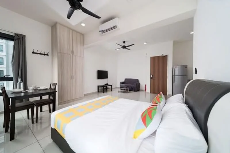 Bedroom features: queen-size bed with white bedding, decorative throw with colorful pattern, 2-blade ceiling fan, wall-mounted TV, grey sofa, dining table with 2 chairs, built-in wardrobe, sliding door, white painted walls, tile flooring, air conditioning unit; style: modern.