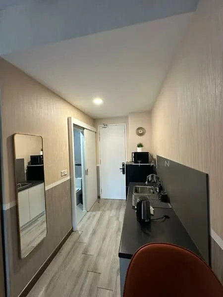 Kitchen features: black countertop, white cabinetry, kitchen sink, stainless-steel kettle, stainless-steel toaster, built-in microwave, refrigerator, wall-mounted mirror, grey textured wall, wood-look tile flooring, recessed ceiling lights, white door, open layout; style: modern.