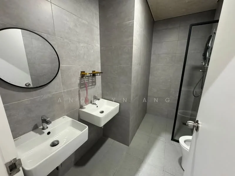 Bathroom features: grey tiled walls, grey tiled flooring, two wall-mounted sinks, chrome basin mixers, round mirror, glass shower enclosure, shower head, toilet, towel rack; style: modern.