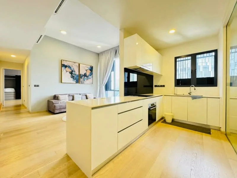 Kitchen features: white cabinetry, black countertop, stainless-steel sink, chrome pull-down faucet, built-in oven, stainless-steel range hood, 4-burner gas hob, recessed downlights, wooden flooring, floor-to-ceiling windows, open layout to living area, grey accent wall; style: modern; view: city. Living features: 3-seater fabric sofa in grey, area rug, wall-mounted TV, coffee table, natural light from windows; style: modern; view: city.