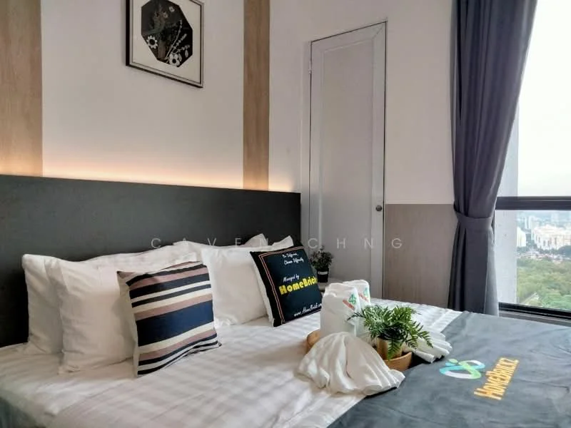 Bedroom features: king-size bed with white bedding, upholstered headboard, decorative throw pillows, bedside table with decorative items, floor-to-ceiling window with city view, grey curtains, wood panel accent wall, wall-mounted artwork, indirect lighting above the headboard, greenery in a decorative pot; style: modern; view: city.