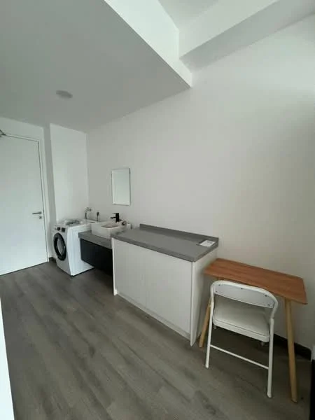 Laundry features: white walls, grey laminate countertop, white cabinetry, washing machine, sink with faucet, wooden table, chair, vinyl plank flooring, recessed ceiling light; style: modern.