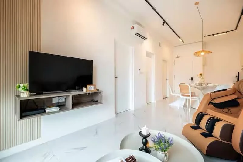 Living features: large flat-screen TV on wall-mounted shelf, wooden TV console, cream painted walls, marble tile flooring, recessed downlights, ceiling-mounted air conditioning unit, pendant light fixture, brown leather recliner chair, white dining table with chairs in background, decorative vase with flowers on coffee table, coffee table with decorative items; style: modern.