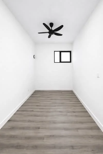 Room features: white painted walls, laminate flooring, 5-blade ceiling fan in black, small window, clock on wall; style: minimalist.